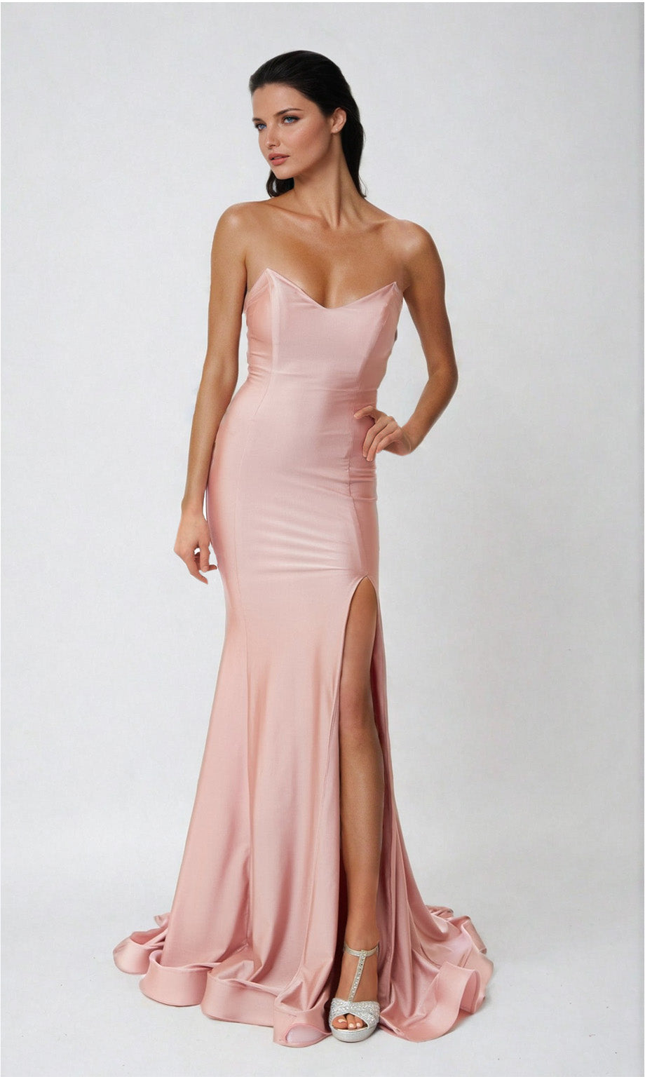 A woman models the Atria 6544H Lace-Up Strapless Long Prom Dress in light pink, featuring a high slit, while standing against a plain white background.